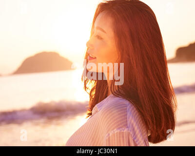 Young Asian woman profiter de la lumière du soleil tôt le matin sur la plage. Banque D'Images