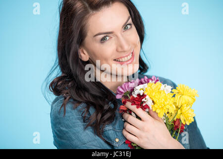 Portrait of happy woman holding Flowers en studio sur bleu Banque D'Images