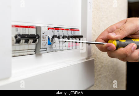 Photo de gros plan electrician installing fusible dans le tableau de bord à l'aide d'un tournevis Banque D'Images