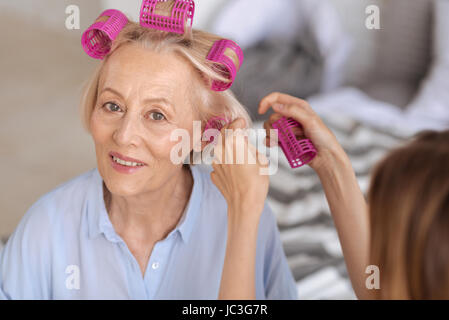 Les mains des femmes aidant à mettre sur hair rollers Banque D'Images