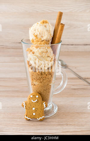 Boules de glaces et d'épice maison Gingerbread chapelure dans une latte de verre. Décorées avec un bâton de cannelle et un Gingerbread man. Rétro-éclairée. Lon Banque D'Images