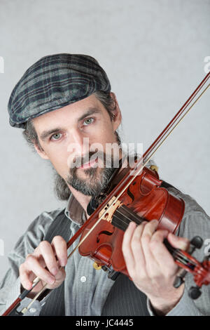 La lecture d'un homme sérieux Irish fiddle sur fond gris Banque D'Images