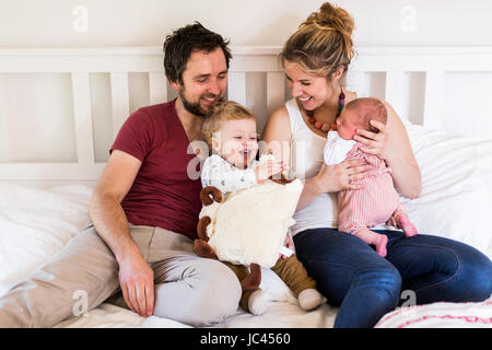 Les jeunes parents dans le lit avec leurs petits enfants Banque D'Images