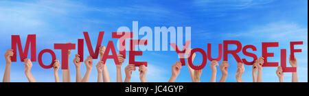 De nombreuses mains tenant les mots rouges vous motiver dans le ciel Banque D'Images