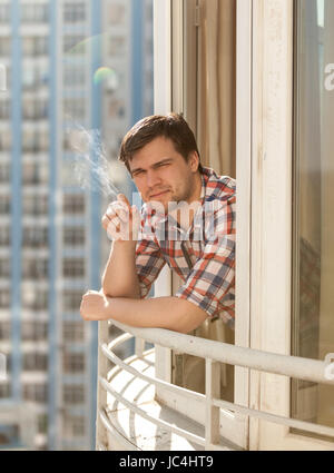 Beau jeune homme cigarette sur balcon Banque D'Images