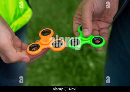 Trendy fidget spinner - deux personnes holding green et orange fidget spinners dans les mains, vue en gros Banque D'Images