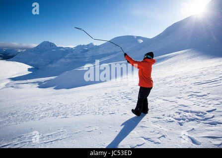 Snowboarder professionnel Robin Van Gyn, montre la façon d'utiliser une sonde d'avalanche sur une journée ensoleillée à Haines, Alaska. Banque D'Images