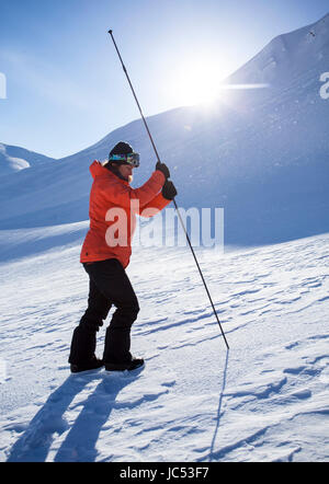 Snowboarder professionnel Robin Van Gyn, montre la façon d'utiliser une sonde d'avalanche sur une journée ensoleillée à Haines, Alaska. Banque D'Images