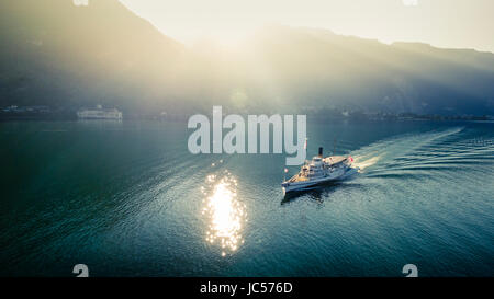 Croisière en bateau sur le lac Léman au coucher du soleil, le soleil se reflétant dans les eaux et avec des montagnes en arrière-plan dans le Canton de Vaud, Suisse Banque D'Images