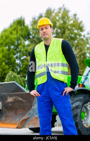 Builder ou conducteur debout devant des machines de construction sur chantier Banque D'Images