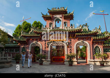 Les femmes vietnamiennes à pied en face de l'entrée de finement décorés le Temple de Quan Cong, un temple chinois datant de 1653 dans la région de Hoi An, province de Quang Nam. Hoi An est une ville historique sur la rivière Thu Bon et était l'un de l'Asie du Sud est le plus important des ports internationaux au 16ème et 17ème siècle ; le vieux quartier avec son architecture particulière est maintenant un site du patrimoine de l'UNESCO et un arrêt populaire pour les touristes. Banque D'Images