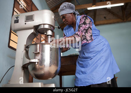 Une femelle Baker en utilisant son mixeur pour faire du pain. La Tanzanie, Afrique. Banque D'Images