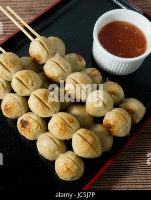L'alimentation et de déguster une cuisine traditionnelle, des grillades sur brochette de bambou boulettes servi avec sauce épicée. Banque D'Images