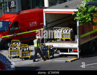 Un London Fire Brigade travailleur se déplace de réservoirs situés à proximité des lieux d'un incendie qui a ravagé les 24 étages de la tour de Grenfell, dans l'ouest de Londres. Banque D'Images