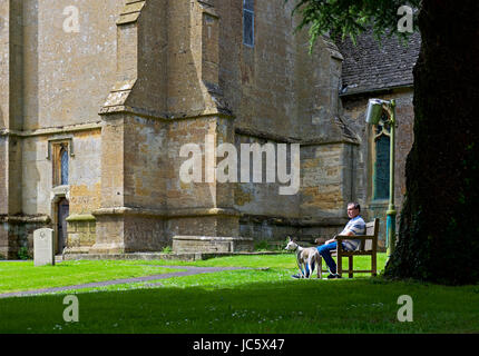 L'homme et le chien et l'église de St Edward's, Stow on the Wold, Gloucestershire, Angleterre, Royaume-Uni Banque D'Images