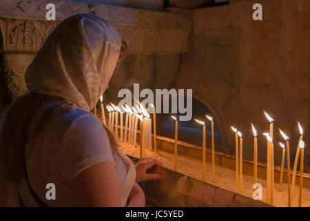Femme aux cheveux couverts récitant une prière dans l'église du Saint-Sépulcre, situé dans le quartier chrétien de la vieille ville de Jérusalem, Israël. Banque D'Images