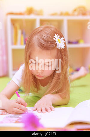 Cute little girl couchée sur le sol et le dessin photo à l'album, s'amusant à la maison, enfance heureuse, avoir le talent de l'art concept Banque D'Images