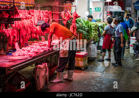 Feux rouges mettent en évidence de nouvelles réductions de la viande sur l'étal du boucher. Marchands au travail, d'interaction avec les consommateurs. Banque D'Images