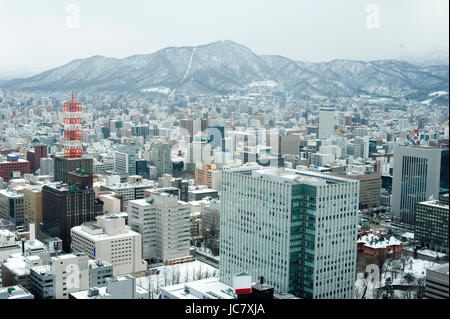 Ville de Sapporo au Japon comme vu de la JR Tower avec la neige sur les bâtiments et d'une vue panoramique montrant la topographie de la montagne derrière l'architecture moderne Banque D'Images