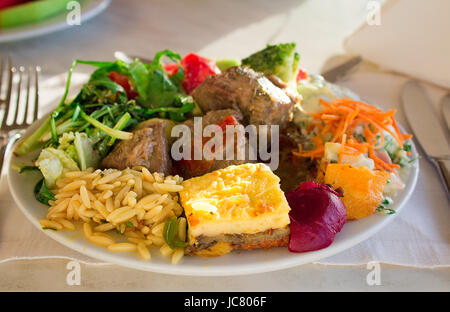 Sur un tissu d'une table le plat avec la viande cuite, une omelette, des légumes est situé. Banque D'Images