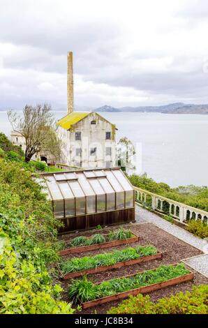 Le pénitencier d'Alcatraz island, maintenant un musée, à San Francisco, Californie, USA. Vue de la maison du pouvoir et une petite serre sur les jardins de fleurs de la prison. Banque D'Images