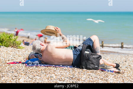Couple de personnes âgées se détendre sur une plage de galets par une chaude journée d'été en juin 2017 à Littlehampton, West Sussex, Angleterre, Royaume-Uni. Banque D'Images