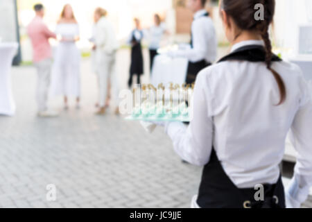 Arrière-plan flou, de garçon portant un plateau de hors-d'œuvre. Partie en plein air avec le doigt de la nourriture, des bonbons. Service de traiteur. Banque D'Images