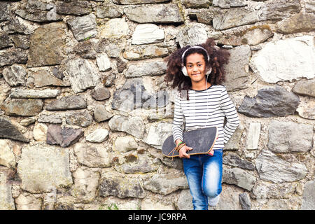 African American Girl with skateboard et écouteurs. Banque D'Images
