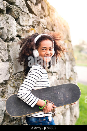 African American Girl with skateboard et écouteurs. Banque D'Images