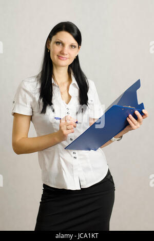 Fille d'entreprise à l'écoute et prend des notes dans un dossier. Elle mène les entrevues. Studio, fond clair Banque D'Images