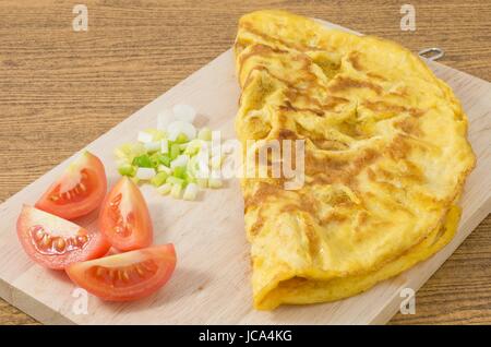 La cuisine thaï et de l'alimentation, de style Thaï délicieux omelette aux tomates et oignon vert haché sur une planche de bois. Banque D'Images