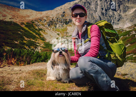 Jeune femme touriste avec chien et lunettes assis sur de hautes montagnes background Banque D'Images