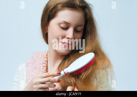 Jeune femme blonde en peignoir comb cheveux après le lavage. Sur fond blanc. Banque D'Images