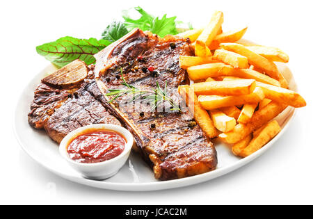 L'aloyau grillé tendre ou t-bone steak servi avec des frites dorées et salade d'herbes fraîches accompagnées d'un barbecue ou sauce ketchup aux tomates Banque D'Images