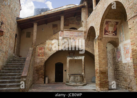 Jolie cour dans le Palazzo del Popolo, avec des fragments de fresques par Sodoma : San Gimignano, Toscane, Italie Banque D'Images