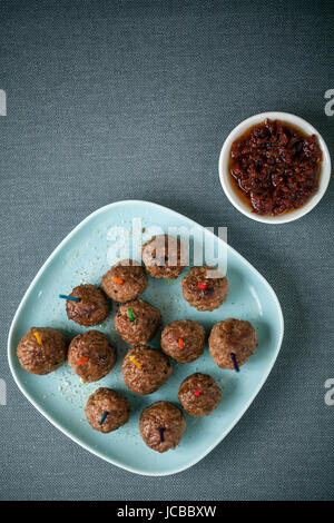 Vue aérienne d'une assiette de boulettes de viande assaisonnée et salé tomate épicé et de piment pour les apéritifs, vue aérienne sur une nappe gris avec copyspace Banque D'Images