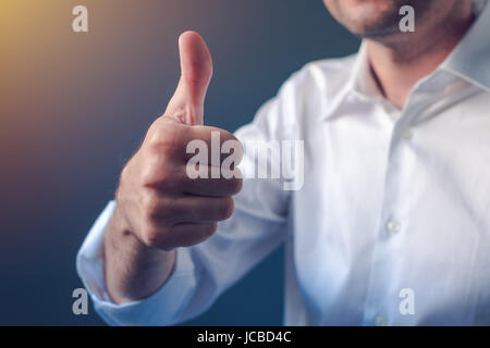 Businessman approuvant avec thumb up geste, personne d'affaires en chemise blanche avec manches retrousser soulignant l'approbation ou de satisfaction Banque D'Images