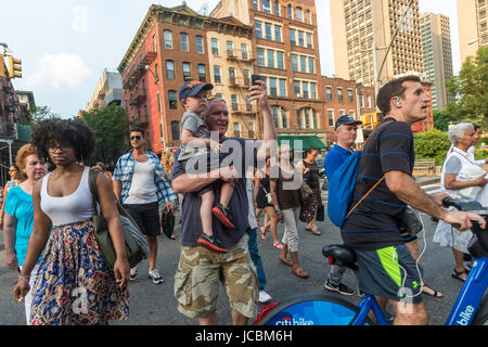 New York, USA - Le père porte son fils et prend un jour selfies pendant la fête de la procession de l'église St Antoine de Padoue, une congrégation américaine italienne traditionnelle, qui est devenu plus petit et plus diversifiée au cours des dernières années en raison d'un voisinage en mutation et de gentrification.©Stacy Walsh Rosenstock Banque D'Images