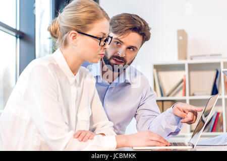 Businessman and businesswoman concentré avec lunettes travailler avec laptop in office Banque D'Images