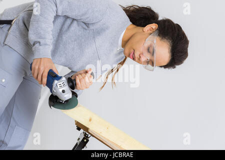 Side view of young female carpenter couper du bois avec tablesaw Banque D'Images