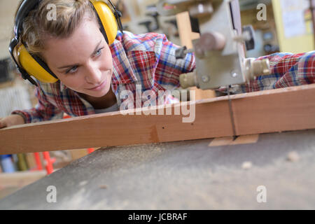 Female carpenter planche en bois de coupe Banque D'Images