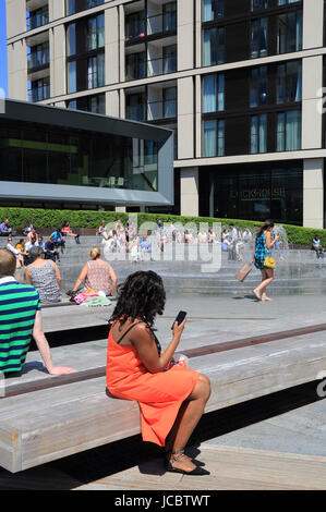 Les gens se détendre par les fontaines à Paddington Basin, à l'ouest de Londres, Royaume-Uni Banque D'Images