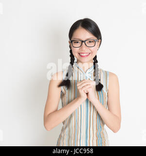 Joyeux Nouvel An chinois ! ! Portrait of Asian Chinese girl accueil, dans un article sur fond uni cheongsam. Banque D'Images