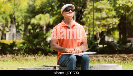 Aveugle hispanique, latino, disability, personne handicapée et de la vie quotidienne. Malvoyants man reading book avec les mains, en touchant la page Banque D'Images