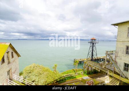 La vieille tour de garde sur l'île pénitencier d'Alcatraz, maintenant un musée, à San Francisco, Californie, USA. Vue de la tour de guet, l'embarcadère où les touristes viennent sur l'île par un ferry et édifices de la vieille prison fédérale. Banque D'Images