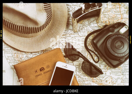 Les essentiels de voyage mis en place, y compris une carte de journal, appareil photo instantané, téléphone, lunettes de soleil, flacon, et chapeau, avec un effet appareil photo vintage, concept de voyage Banque D'Images