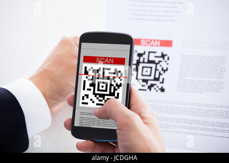 Close-up of Businessman scanner un code barre Using Cell Phone Banque D'Images