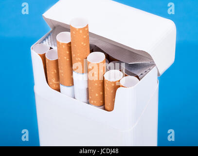 Photo de Cigarettes en paquet sur fond bleu Banque D'Images