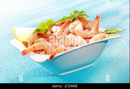 Les fruits de mer délicieux avant-goût de crevettes grillées ou des crevettes roses dans un plat servi avec une tranche de citron et de salade verte sur un fond bleu turquoise Banque D'Images