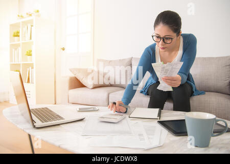 Course mixte chinois asiatique femme au foyer le calcul du budget de la nouvelle année comptable la tenue d'une réception à l'aide de la calculatrice dans le salon à l'hom Banque D'Images